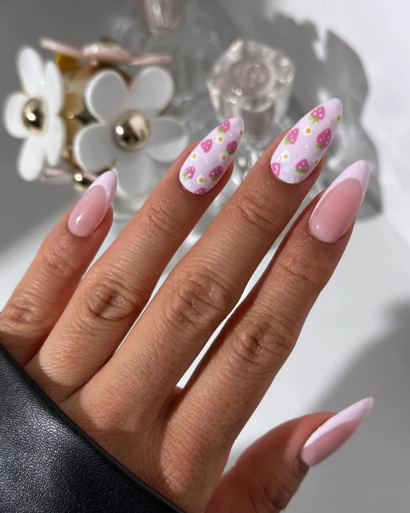 Long almond-shaped nails with alternating solid pink and white base with pink heart patterns, photographed with decorative white flowers in the background.