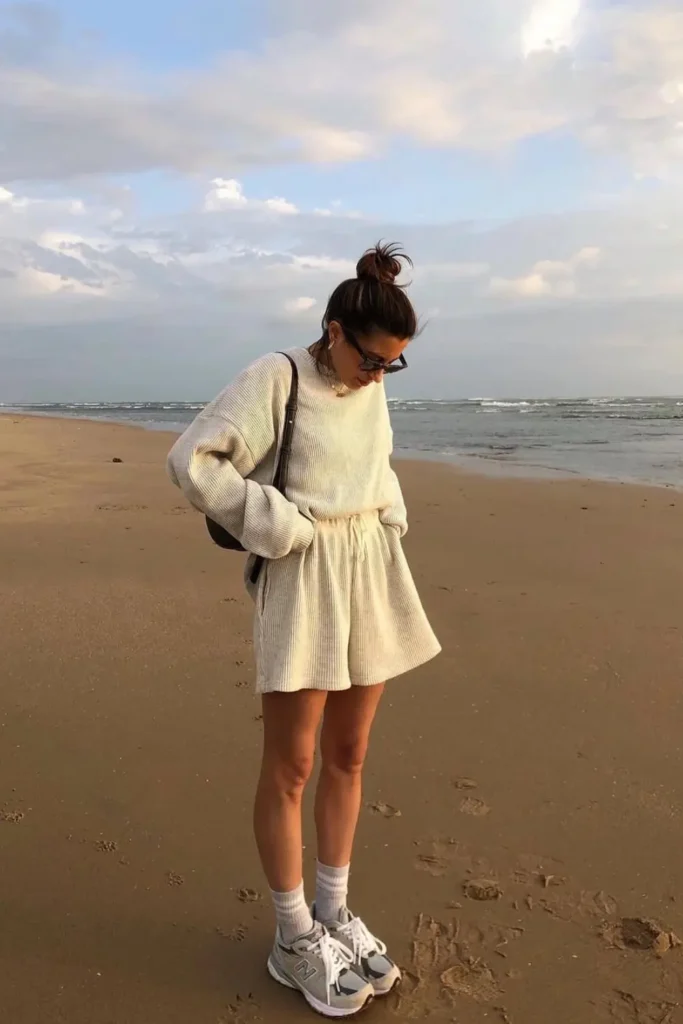 Relaxed coastal style with a cream sweatshirt dress, white sneakers, and socks. A comfortable yet chic beach outfit for springtime strolls.