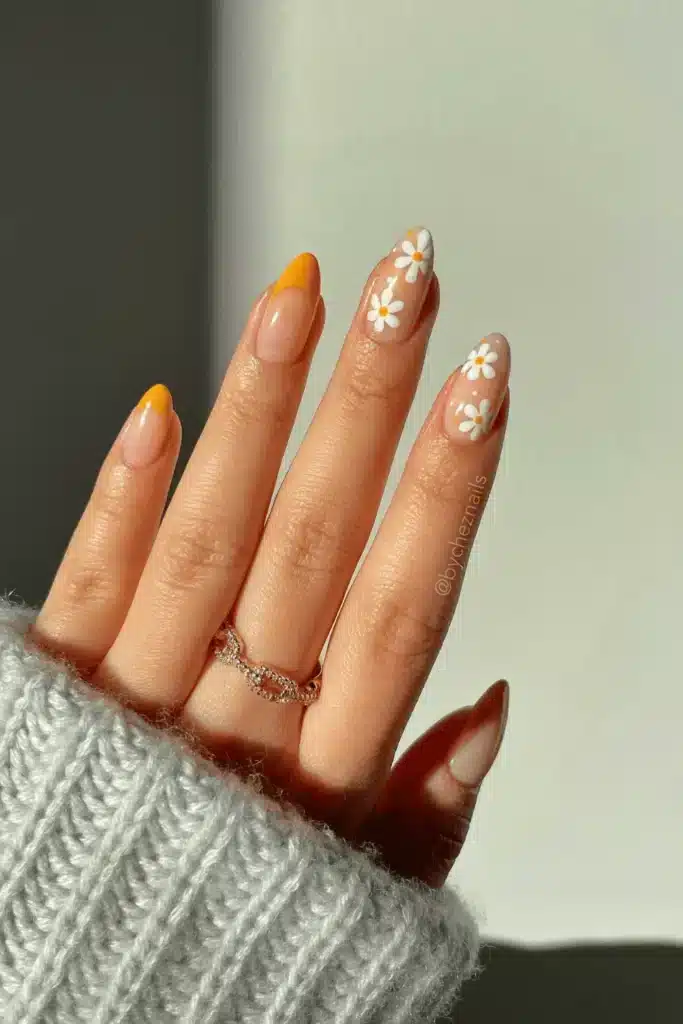 Citrus Daisy Dreams nail design featuring vibrant orange and yellow hues, delicate daisy patterns, and a fresh spring-inspired look.