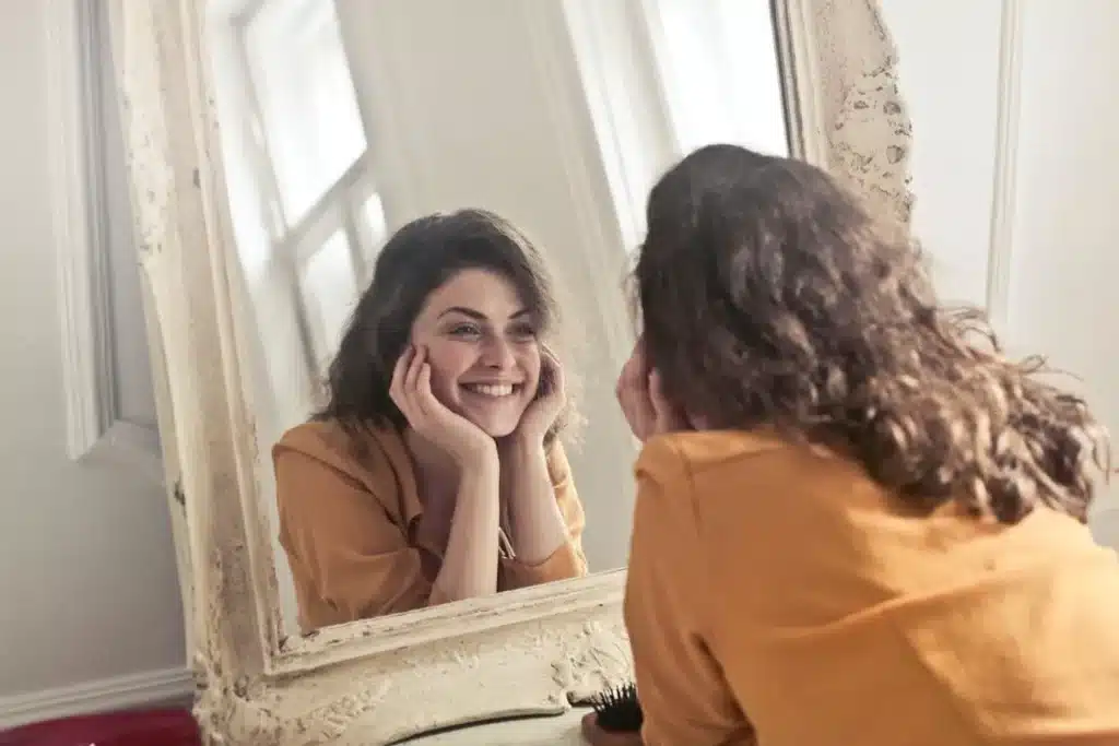 Person saying positive affirmations in mirror for morning self-care routine