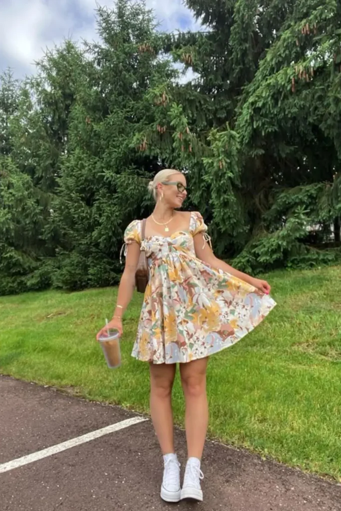 A cheerful floral dress featuring sunny yellow accents and an empire waistline, styled with classic white sneakers. A perfect spring outfit for farmers' markets, park picnics, and weekend adventures, balancing femininity with everyday comfort.