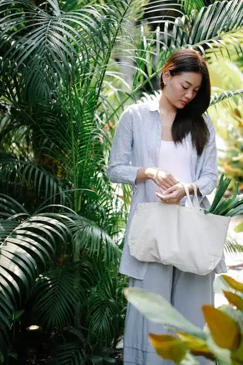 Person with tote bag selecting fresh produce at farmers market