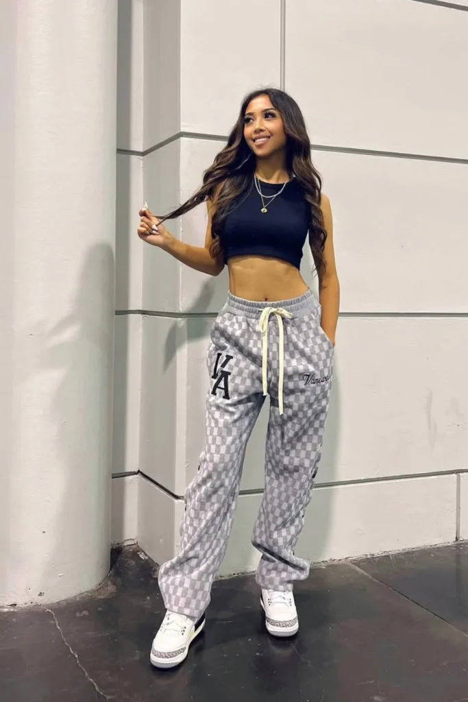 Trendy urban athleisure look with a navy crop top, checkerboard pattern lounge pants, and white sneakers. A stylish mix of comfort and designer fashion for city outings.