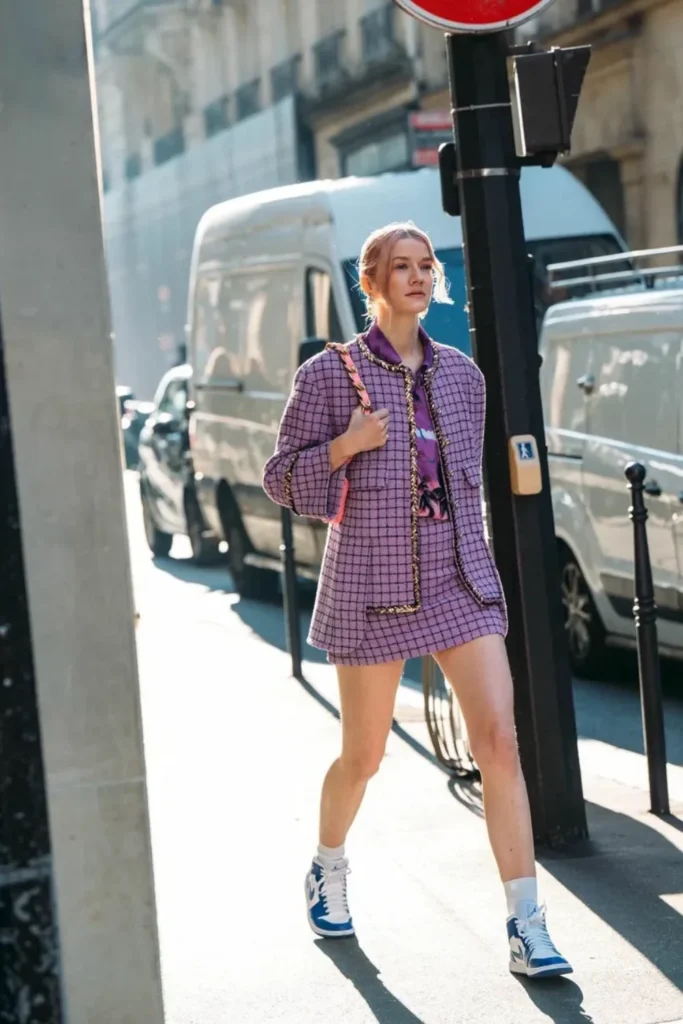 Elegant yet casual outfit with a purple tweed skirt suit featuring decorative trim. Paired with blue and white sneakers, this stylish urban look blends classic sophistication with contemporary comfort.