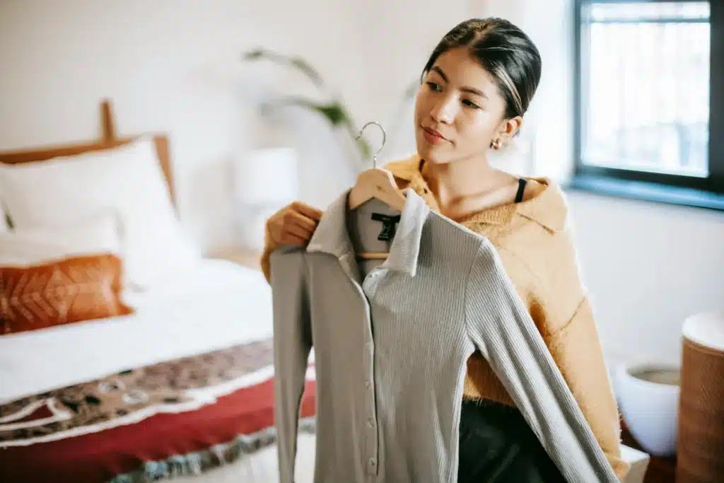 Person creating outfits during bedroom fashion show self-care activity